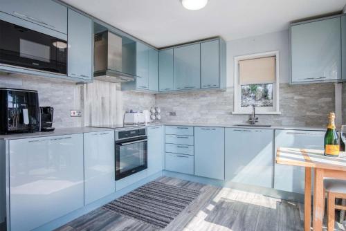 a kitchen with blue cabinets and a wooden table at Lundy Lodge – 1 Bedroom Annex – Rhossili in Rhossili