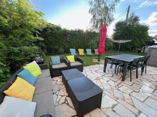 eine Terrasse mit Sofas, einem Tisch und Stühlen in der Unterkunft L'Escapade, Proche Carré-Sénart et Disneyland in Combs-la-Ville