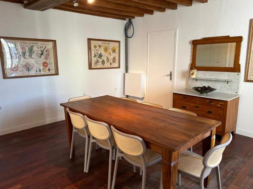 ein Esszimmer mit einem Holztisch und Stühlen in der Unterkunft Maison de campagne familiale in LʼHabit