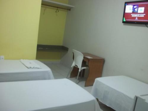 a room with two beds and a tv on the wall at Opara Palace Hotel in Juazeiro