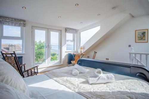 a bedroom with a bed with a blue headboard and windows at Overland Road – 4 Bedroom House – Mumbles in The Mumbles