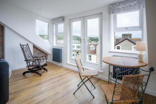 a living room with a table and chairs and windows at Overland Road – 4 Bedroom House – Mumbles in The Mumbles