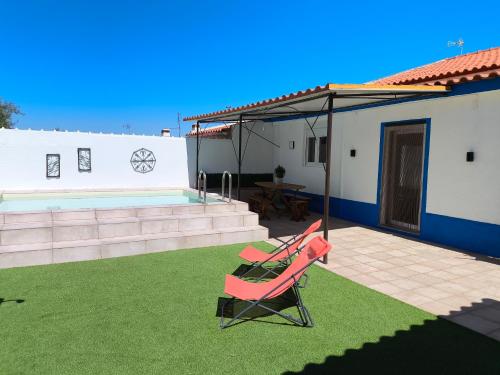 a pink chair sitting on a lawn next to a house at Casa da Courela do Olival - Santo Aleixo
