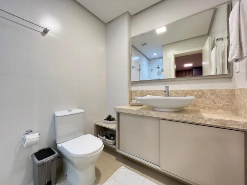 a bathroom with a white toilet and a sink at Apartamento Villaggio Del Veneto 1 dorm by Achei in Canela