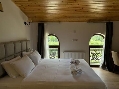 a bedroom with a large white bed with two windows at Gonadze Vineyards Hotel in Ambrolauri
