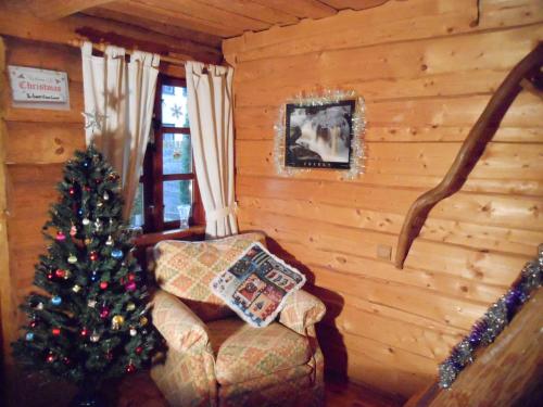 a living room with a christmas tree and a chair at Forest Edge Lodge in Rīga