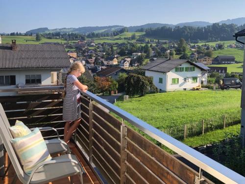 a woman standing on a balcony looking at the valley at Ferienwohnung Marianne in Egg