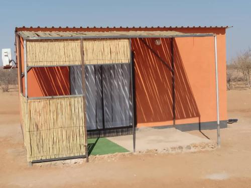 een klein gebouw met een poort in de woestijn bij Petrified forest restcamp in Khorixas