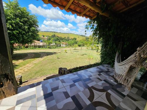a porch with a hammock and a view of a field at Chalés Vila Carrancas - Ao lado do centro com piscina, cozinha completa e muita tranquilidade in Carrancas