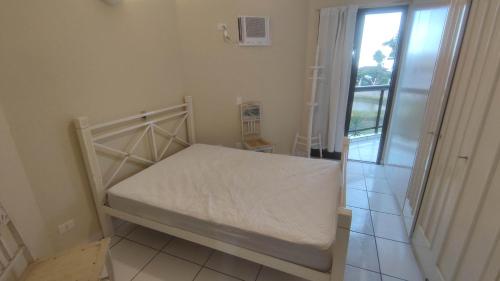 a small white bed in a room with a window at Apartamento Largo dos Coqueiros in Riviera de São Lourenço