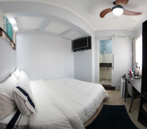 una camera con letto bianco e ventilatore a soffitto di Santo Antônio Hotel Ltda ad Angatuba