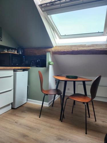 une cuisine avec une table et deux chaises ainsi qu'une fenêtre dans l'établissement Sous les toits de Triboulet, à Blois