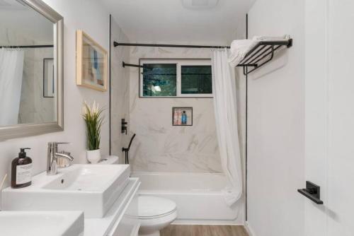 a white bathroom with a tub and a toilet and a sink at Comfortable Kirkland Home for Family & Remote Work in Kirkland