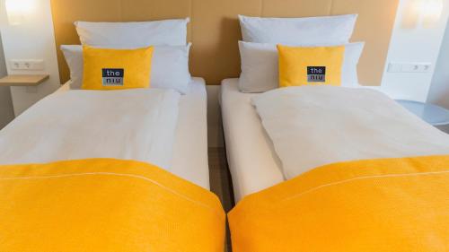 two beds with orange pillows in a room at Holiday Inn - the niu, Dairy Haarlem in Haarlem