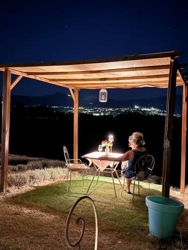 a woman sitting at a table under a pergola at La Lavandula in Poppi