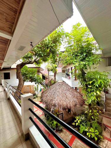 a building with a balcony with trees and a straw umbrella at Papierus Pensionne in Kalibo