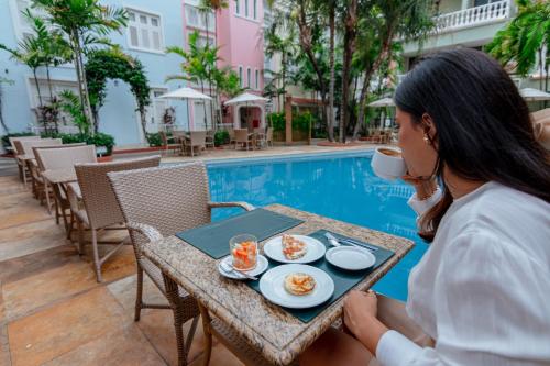 uma mulher sentada à mesa com uma chávena de café em Hotel Villa Mayor Charme em Fortaleza