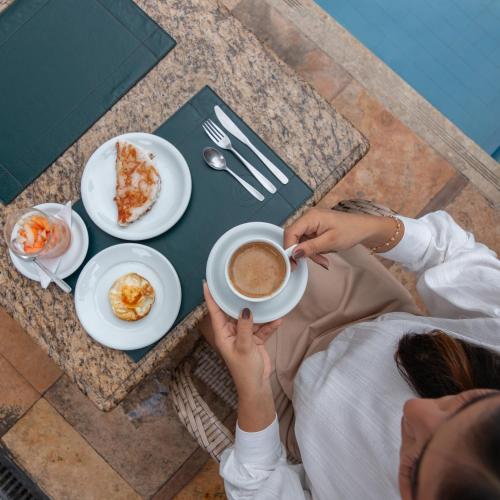 uma pessoa sentada à mesa com uma chávena de café em Hotel Villa Mayor Charme em Fortaleza
