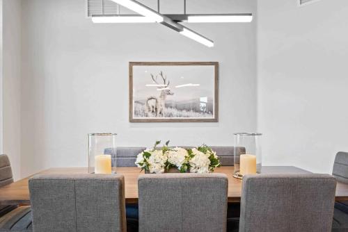 a dining room table with two chairs and a deer picture at One Beaver Creek 54 by East West Hospitality in Avon
