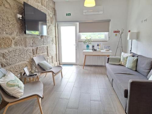 a living room with a couch and a stone wall at Villa Boas House in Castro Daire