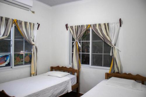 two beds in a room with two windows at Villas Julie in Tela