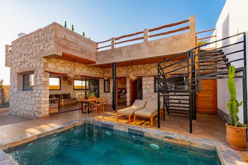 a house with a swimming pool and a patio at Smaylo Surf House in Sidi Kouaki