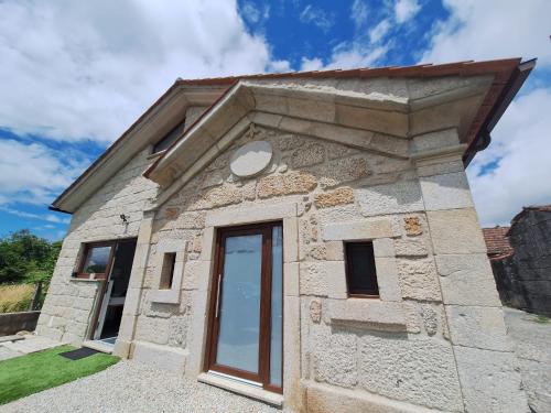 a small stone building with a glass door at Villa Boas House in Castro Daire