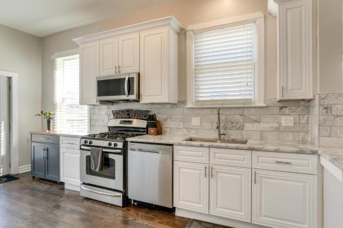 a kitchen with white cabinets and a stove and microwave at Spacious Chicago Condo with Deck Less Than 9 Mi to Downtown! in Oak Park