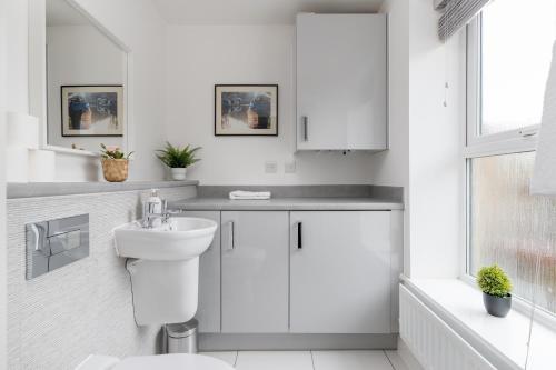 a white bathroom with a toilet and a sink at 4 Bedroom House By Humming Nest Short Lets & Serviced Accommodation Milton Keynes With Free WiFi & Parking in Milton Keynes