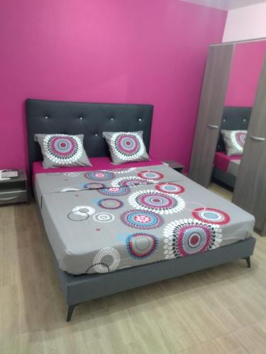 a bedroom with a bed with a pink wall at Residence l oiseau des iles in Grand-Bourg