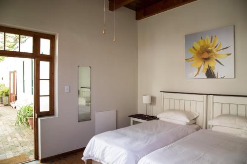 2 camas en un dormitorio blanco con una flor en la pared en 22 Van Wijk Street Tourist Accommodation en Franschhoek