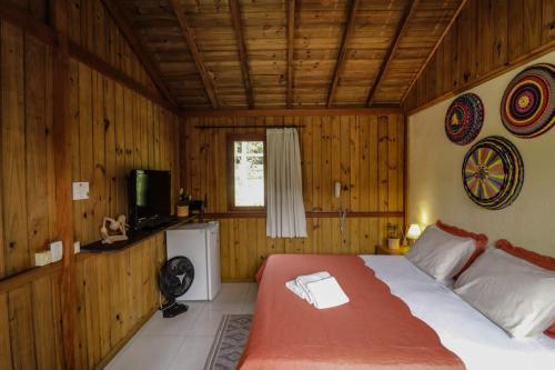 a bedroom with a bed in a room with wooden walls at Pousada Zululand in Guarda do Embaú