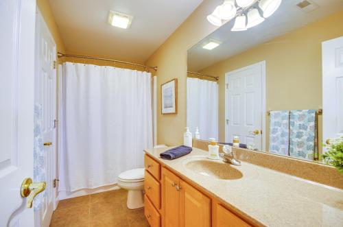 a bathroom with a sink and a toilet and a mirror at Pool Access, Water Views Lake Ozark Condo! in Lake Ozark
