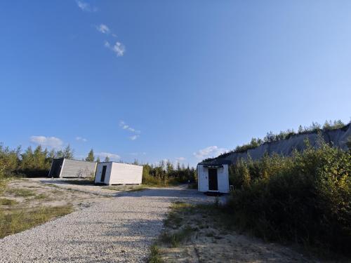 a gravel road with two buildings on the side at RUMMU Quarry Houses in Rummu