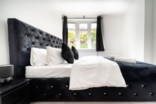 a bedroom with a large bed with a black headboard at LUX 2BDR Flat By Luton Station, Airport, City Centre - 30min to King's X St Pancras International in Luton