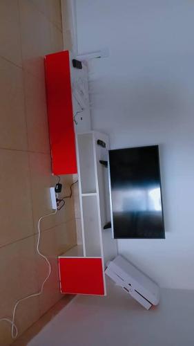 Una habitación con televisor de pantalla plana y armarios rojos. en Résidence EDEN Bamako, en Bamako