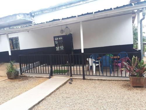 a fence in front of a house with chairs at Résidence LIBOUGA - Edéa I in Edéa