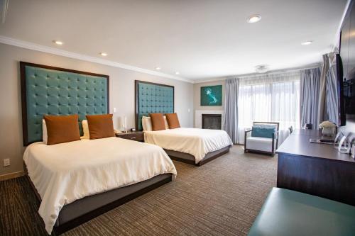 a hotel room with two beds and a desk at Munras Inn in Monterey