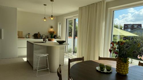 a kitchen and dining room with a table and a window at House W - North Sea Stays in De Haan