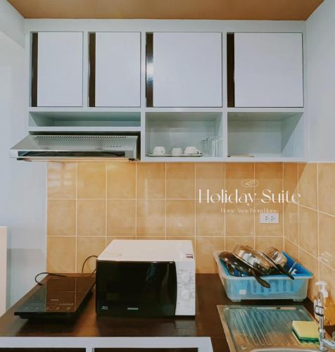 a kitchen with a counter top with a microwave at 2BR Holiday Suite Hat Yai in Hat Yai