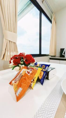 a white bed with a bouquet of flowers and chips at 2BR Holiday Suite Hat Yai in Hat Yai