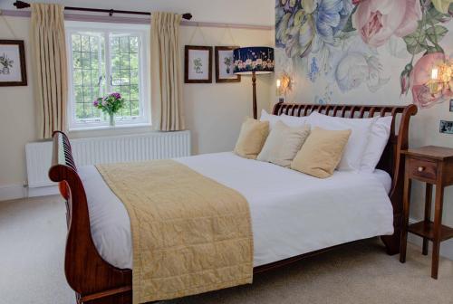 a bedroom with a bed with white sheets and a window at The Grange at Oborne in Sherborne