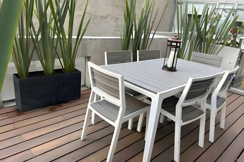 a white table and chairs on a deck with plants at Inigualable estudio en Condesa in Mexico City