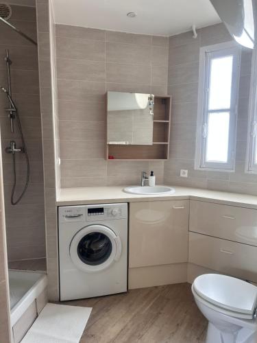 une salle de bain avec une machine à laver et un lavabo dans l'établissement Belleville, à Paris