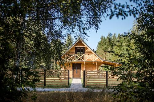 a wooden house with a fence in front of it at Leśny domek in Białowieża