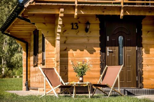 two chairs and a table in front of a cabin at Leśny domek in Białowieża