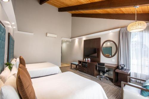 a hotel room with two beds and a desk and a mirror at Munras Inn in Monterey