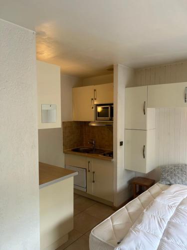 une petite cuisine avec des placards blancs et un canapé blanc dans l'établissement Appartement centre ville, à Chamonix-Mont-Blanc