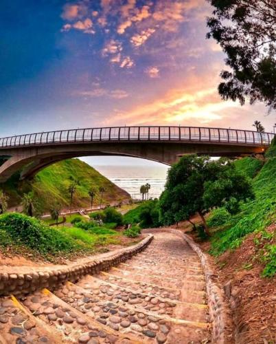 a bridge over a dirt road with a bridge over the water at Maywa at Central Miraflores in Lima