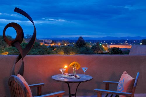 a table with a candle and two chairs on a balcony at Inn & Spa at Loretto in Santa Fe